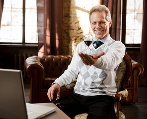 Portrait of handsome psychiatrist man smiling and looking at camera. Psychiatrist man holding and representing hourglass in hand while waiting for patients in his office.