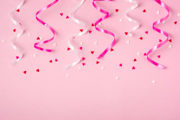 Delicate pink party background with streamers for celebrating with scattered confetti