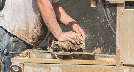 man cutting a stone with a water saw