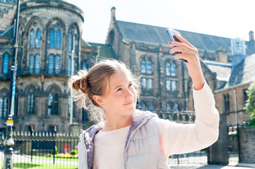 Cheerful girl taking selfie in Glasgow historical place. Traveling.