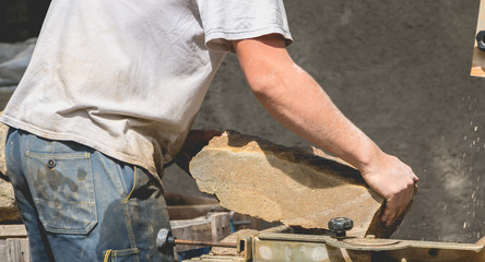 man cutting a stone with a water saw