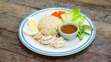 Hainanese chicken rice with boiled egg on a wooden table.
