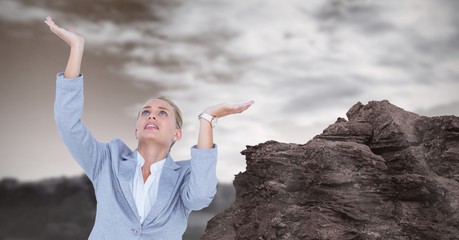 Businesswoman with arms raised by rock