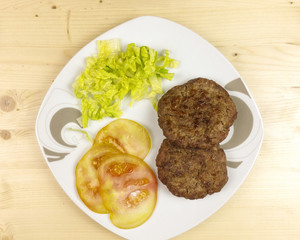 Hamburgers in a plate on wooden background - top view
