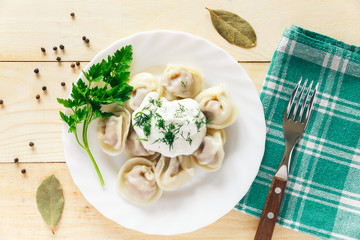 Plate with boiled dumplings served with parsley and sour cream