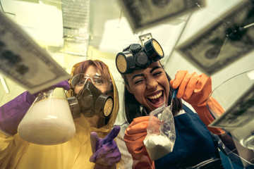 low angle view of women in respirators preparing drugs in laboratory, drugs concept