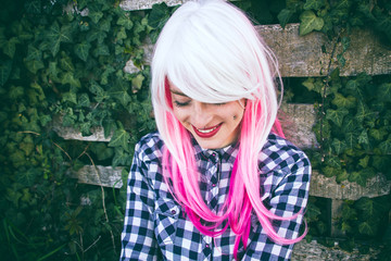 Chica adolescente alternativa con el pelo rosa y blanco, que lleva piercings, con un fondo de...