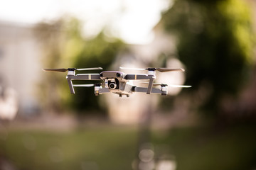 drone quad copter with high resolution digital camera flying hovering in the blue sky over the city