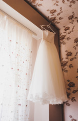 wedding dress on a hanger in room. Wedding morning.