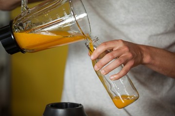 Male staff pouring juice in a bottle - Powered by Adobe