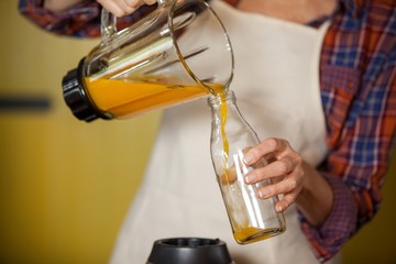 Female staff pouring juice in a bottle