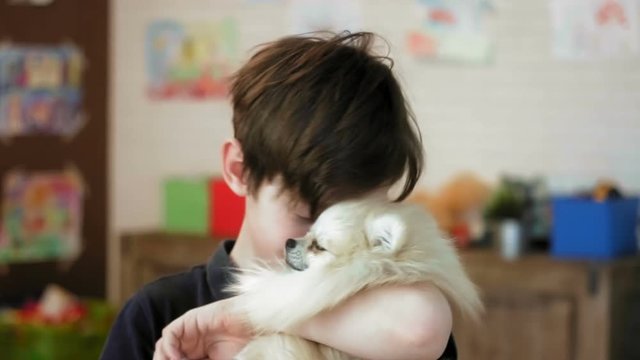 Portrait of a cute little boy hugging his little dog smiling and looking at the camera