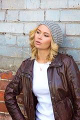 Beautiful fashionable girl stands near the brick wall