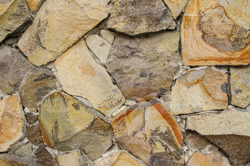 Wall lined with stones. / The wall is lined with beige cobblestones of various sizes fastened with concrete.