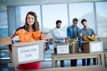 Smiling woman holding a donation box in office - Powered by Adobe