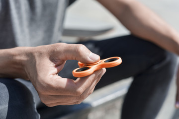 young man playing with a fidget spinner - obrazy, fototapety, plakaty