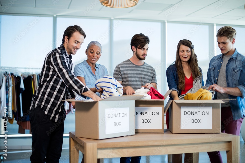 Wall mural Creative business team sorting clothes in donation box