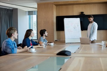 Man giving presentation to her colleagues in conference room