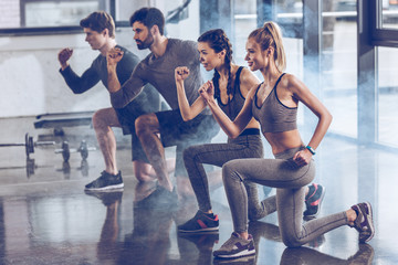 group of athletic young people in sportswear doing lunge exercise at the gym, aerobic fitness concept