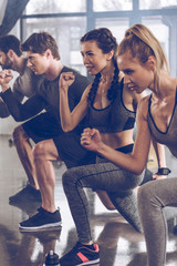 group of athletic young people in sportswear doing lunge exercise at the gym, aerobic fitness concept - obrazy, fototapety, plakaty