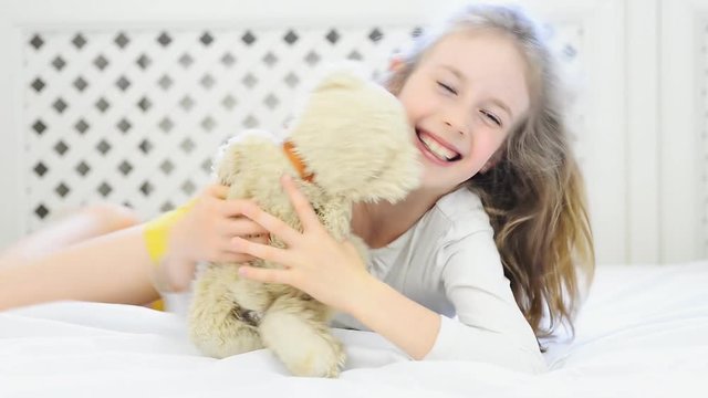 Little girl playing with toy on the bed.