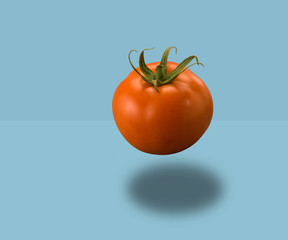 Tomato floating on blue background
