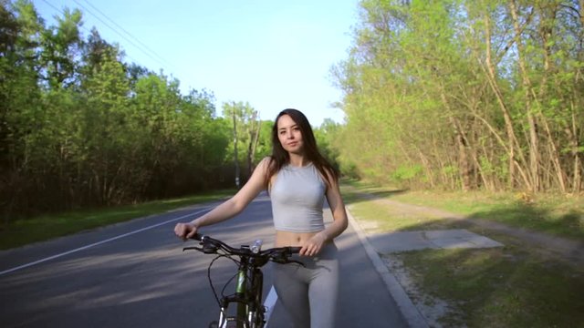 Young mixed race woman cyclist with mountain bike walking in the forest beetween cycling workout outdoor. Healthy lifestyle concept.