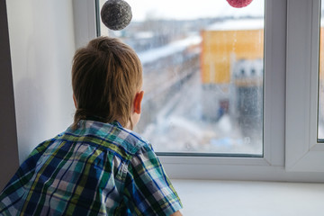 Close up view of little boy looking out of window