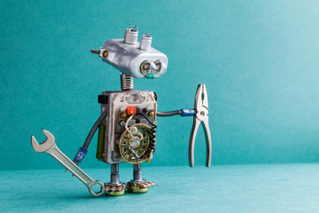 Electrician robot handyman wrench pliers. Mechanic cyborg toy lamp bulb eyes head, electric wires, capacitors vintage resistors. Green paper background copy text.