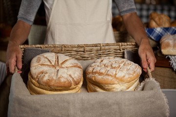 female staff holding wicker basket of breads 
