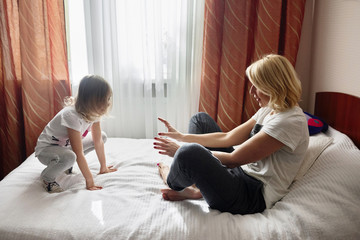 Little girl and her mother are playing at bedroom