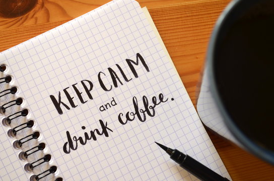 KEEP CALM AND DRINK COFFEE written in notebook with cup of coffee