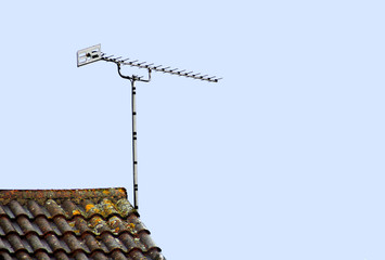 A roof top tv aerial against a clear pale blue sky