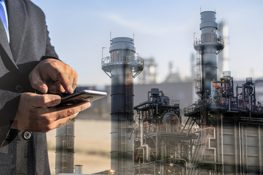 Double exposure of businessman checking oil refinery industry plant by smart phone in the night as Energy and Technology concept