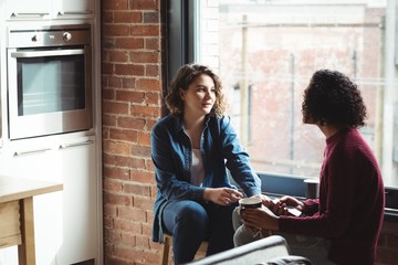 Lesbian couple holding hands while having coffee