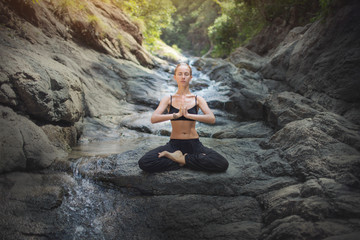 Meditation,serenity and yoga practice.Woman sitting in the lotus position on the rocks at the...