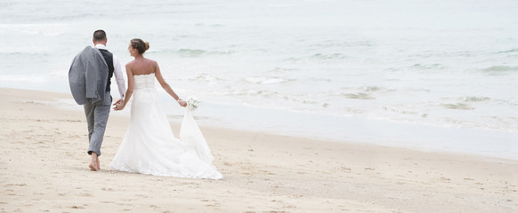 Back view of bride and groom walking on the beach