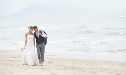 Happy bride and groom walking on the beach
