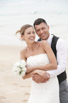 Portrait of happy bride and groom embracing each other at the beach