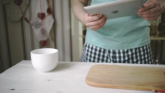 Man using tablet pc in kitchen. Man hand holding tablet pc in kitchen. Close up of man touch tablet screen morning kitchen. Chef research tablet computer in home kitchen