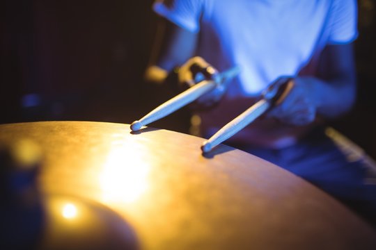 Mid section of drummer playing drum in nightclub