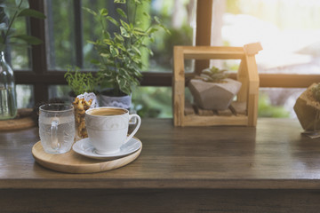 Cup of hot coffee in circle wooden tray on wooden counter in coffeeshop
