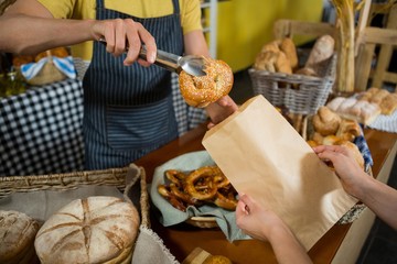 Mid section of staff packing croissant in paper bag at counter