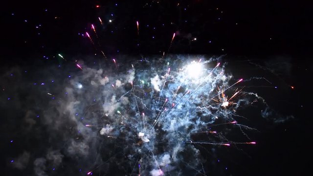 Fireworks exploding in various colors in the dark night sky during a celebration.