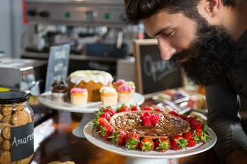 Smiling male customer smelling strawberry pie at counter
