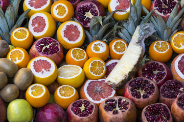 Background of fresh fruits of pomegranate oranges kiwi, pineapple 