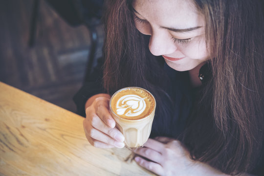 Top view image of Asian woman holding coffee cup and smelling hot coffee with feeling good in cafe