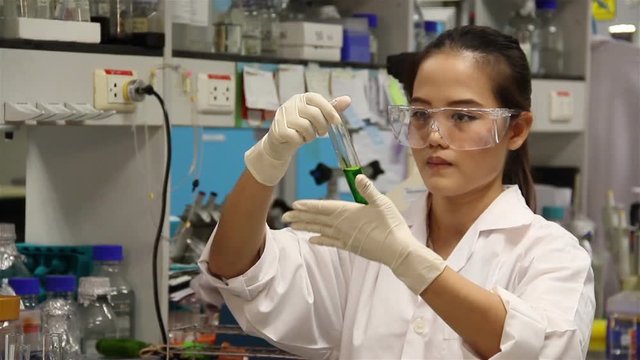 Female Scientist is Mixing chemicals for research in laboratory.
