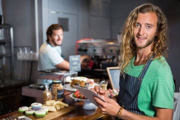 Male staff writing on clipboard at counter