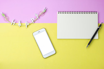 flat lay photo of blank notebook, pencil, smart phone and happy wooden clipswith copy space background, minimal style